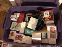 Plastic bin filled with approximately 30 plus Hallmark Keepsake Ornaments in their boxed packaging, showing a mixture of sizes and colors.