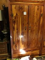 Front view of red cedar wardrobe showing double doors with wood grain and lock hardware.