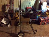 Photo of assorted tools, boxes, and yellow rope on a table with a metal dolly cart in front