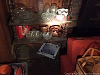 Wooden shelf holding various glassware and decorative items, including clear cut glass bowls, glass bottles, wooden containers, and a heart-shaped box.