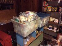 Two large plastic bins stacked, filled with sealed plastic bags containing unopened Happy Meal toys.