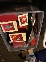 Plastic bin packed with multiple Hallmark Keepsake Ornament boxes and party supplies including paper plates and napkins.