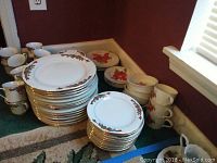 Overview of stacked dinner plates and cups with poinsettia and Christmas ribbon designs.