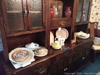 Wide view of wooden cabinet with assortment of china pieces mainly cups, saucers, pitchers, serving dishes and decorative plates