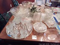 Photo showing crystal and glassware pieces on a table including bowls, decanter, cups, and serving dishes, illustrating quantity and cut crystal patterns.
