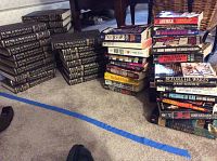 Multiple volumes of Funk & Wagnalls New Encyclopedia in black and gold hardbound covers stacked on carpet floor.