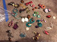 Overview of assorted costume jewelry earrings in various colors and styles laid out on carpet