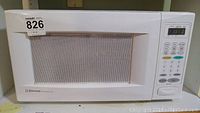 White Emerson microwave oven front view showing door, mesh window and control panel.