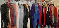 Rack of assorted women's clothing including coats, dresses, skirts, blouses in various colors and materials hung on a rack