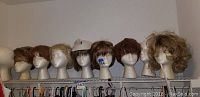 7 wigs displayed on Styrofoam heads in a row on a shelf