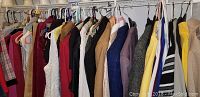 Photo of approximately two dozen women's clothing items hung on a rack, showing various colors and materials including textured knitwear and patterned fabrics.