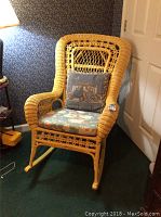 Front and side views of a natural wicker rocking chair with floral seat and back cushions, showing woven details and some paint damage on the legs.