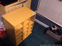 Yellow wooden shoe storage cabinet with 12 cubby holes and worn yellow paint.