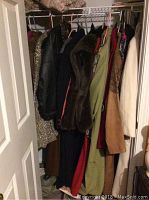 View of hanging women's coats and jackets in dark and neutral colors, including faux fur cape and leather jacket.