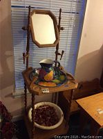 Wooden wash stand with mirror, ceramic pitcher and bowl on the top shelf.