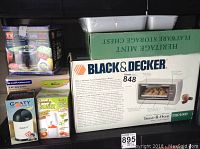 Photo showing boxed Black & Decker Toast-R-Oven, flatware storage chest, Graty cheese grater, Speedy Slicer on shelf.