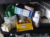 Photo showing Brita water filter pitcher, replacement filter box, Coleman cooler, yellow plastic organizer, green watering can, and assorted containers.
