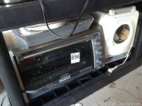 Convection small oven, breadmaker, and portable BBQ on a black shelving unit, showing the oven with some wear spots on the glass door
