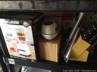 Black & Decker blender box, charcoal grill top piece, cardboard box, and yellow knife block with knives on shelf