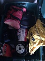 Photo of various automotive accessories including booster cables, floor mats, and bags inside a plastic bin.