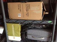 Variety of suitcases, soft-sided bags, and a cardboard box stacked on plastic shelving.