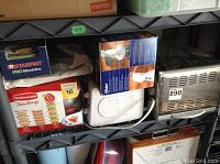 Photo showing Rubbermaid Take Alongs variety pack, Starfrit Pro Mandoline slicer box, Oster toaster oven, Oster hand blender, and Hillary enamel coffee set box all on shelves.