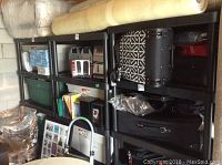 Photo showing black plastic shelves filled with various household items including bags, storage bins, and boxes.