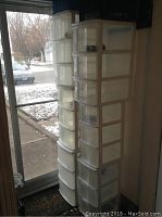Two plastic drawer units standing side by side near a door, each unit containing three translucent drawers within a white plastic frame, mounted on wheels.