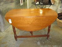 Closed view of wooden drop leaf dining table showing half circle shape and medium brown finish