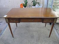 Another angled shot showing the desk surface, drawer layout, and leg design with visible scratches and discoloration.
