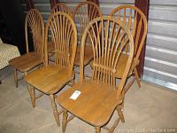 View of six wooden dining chairs grouped together showing matching and pair designs.