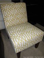 Frontal view of the upholstered chair showing the yellow geometric patterned fabric on seat and backrest with wood legs.