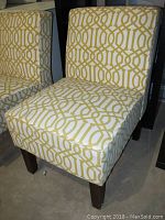 Front and angled view of the upholstered chair showing yellow geometric patterned fabric and dark wood legs.