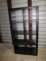 Front view of black IKEA cubby bookshelf with 8 compartments showing surface scratches and marks.