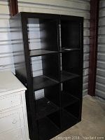 Front and slight side view of IKEA cubby bookshelf showing six square compartments, dark finish, scratches visible.