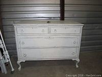 White distressed wooden four drawer dresser from front, showing scratches and overall condition