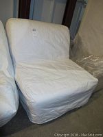 Fold out chair cot in folded position covered in white fabric with some stains, photograph taken to show condition and style of the item.