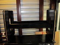 Black wooden table base with gold accent, showing top support and side panels with gold edging and wear marks.