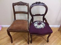 Photo shows two vintage wooden chairs side by side, one with a tan seat and floral carved crest, the other with a round back and purple floral needlepoint seat.