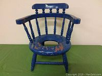 Front view of vintage blue wooden child's potty chair showing wear and paint chipping on seat and armrests.