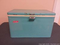 Front exterior view of blue Coleman cooler showing metal latch and logo
