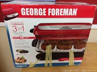 Box of George Foreman Evolve 3-in-1 Grill showing grill function cooking meat and features including 42% fat removal and removable plates.