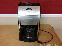 Front view of the Cuisinart coffee maker showing the full unit with glass carafe and power cord.