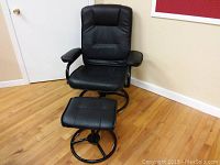 Full view of black chair with cushioned seat and back and circular metal base