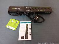 Embertec Emberstrip 8AV+ surge protector power strip with 8 outlets, remote control attached to main power cord, user manual and instruction card laid out on a flat surface.