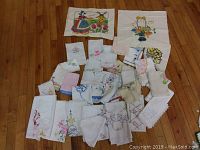 Overview of all vintage embroidered linens and handkerchiefs laid out on wooden floor