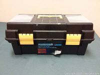Black plastic Mastercraft tool box with yellow latches and handle, showing front and lid compartments.