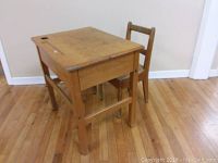 Side view of child's wooden school desk with chair, showing structural details and wear.