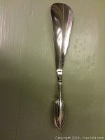 Front view of sterling silver shoe horn showing full length and decorative handle with detailed patterns.