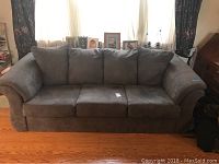 Front view of the slate gray microfiber sofa with three seat cushions and attached back cushions.